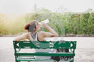 Beautiful woman feel tried and thirsty, itâ€™s sunny day. Charming beautiful girl sit on bench at park and take a rest, feel Stock Photo